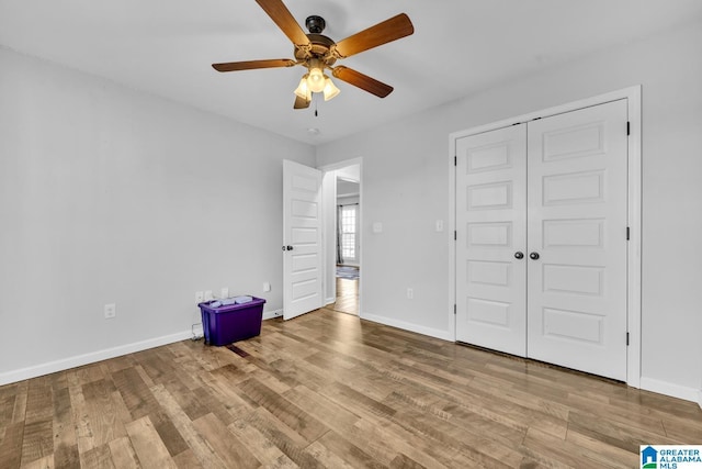 unfurnished bedroom with ceiling fan, light wood-type flooring, and a closet