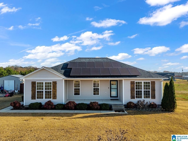 single story home with a standing seam roof, metal roof, a front lawn, and solar panels