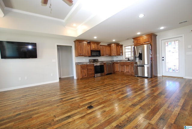 kitchen with ornamental molding, stainless steel appliances, ceiling fan, dark wood-type flooring, and a kitchen island