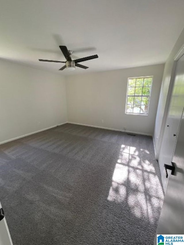 unfurnished room featuring ceiling fan and dark carpet