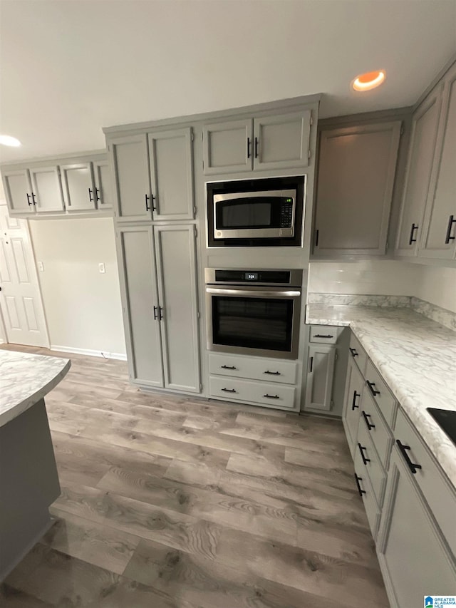 kitchen featuring gray cabinetry, light hardwood / wood-style floors, and appliances with stainless steel finishes