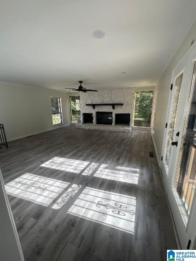 unfurnished living room featuring a fireplace, dark hardwood / wood-style flooring, and ceiling fan