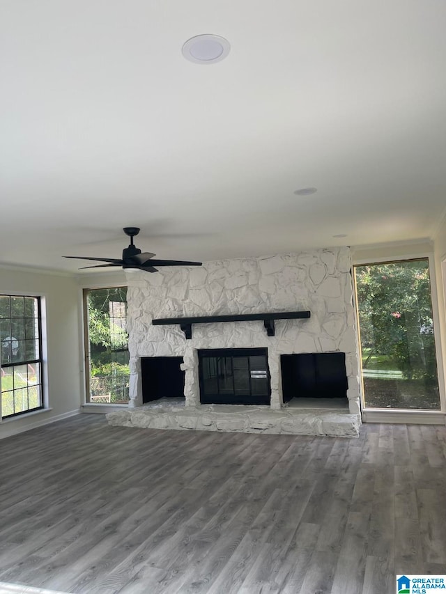 unfurnished living room featuring ceiling fan, a stone fireplace, and wood-type flooring