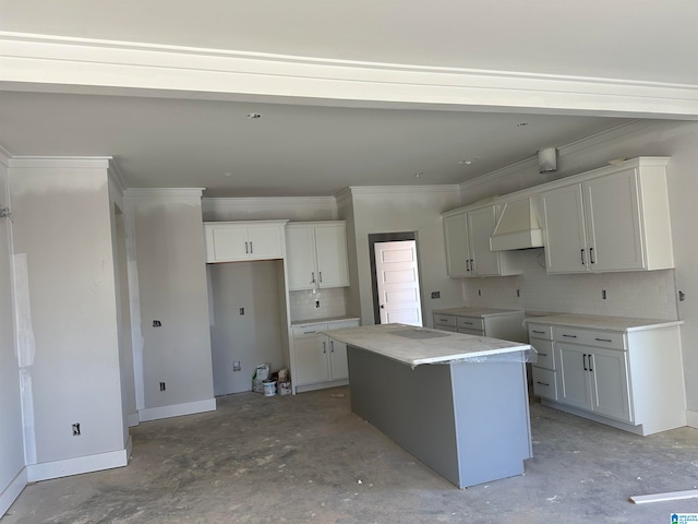 kitchen with white cabinetry, a kitchen island, tasteful backsplash, and ornamental molding