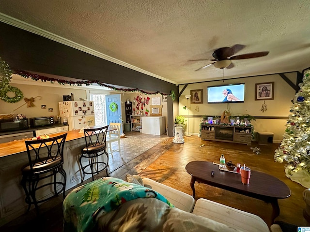 living room with hardwood / wood-style floors, a textured ceiling, ceiling fan, and ornamental molding