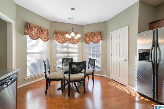 dining area with hardwood / wood-style flooring, a healthy amount of sunlight, and an inviting chandelier