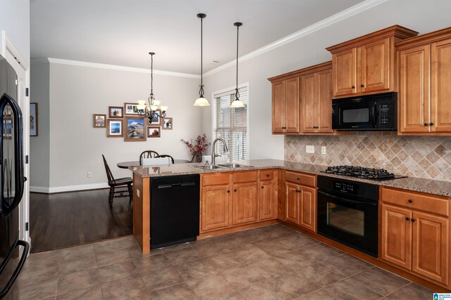 kitchen with light stone countertops, kitchen peninsula, sink, black appliances, and hanging light fixtures