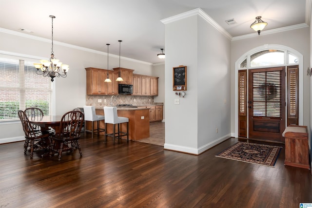 foyer with a chandelier, dark hardwood / wood-style flooring, and crown molding