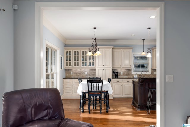 kitchen with light wood-type flooring, hanging light fixtures, and tasteful backsplash