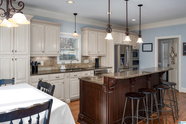 kitchen featuring sink, dark wood-type flooring, dark stone countertops, decorative light fixtures, and appliances with stainless steel finishes