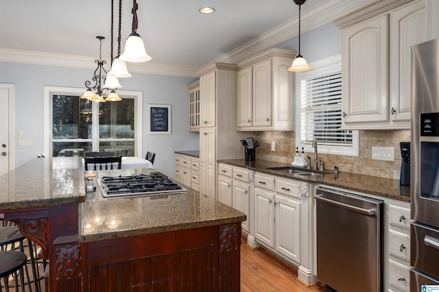 kitchen featuring dark stone countertops, ornamental molding, decorative light fixtures, a kitchen island, and stainless steel appliances