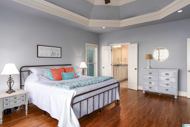 bedroom with crown molding, ensuite bath, dark hardwood / wood-style floors, ceiling fan, and a tray ceiling