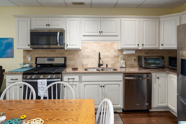 kitchen featuring white cabinetry, sink, a drop ceiling, dark wood-type flooring, and appliances with stainless steel finishes