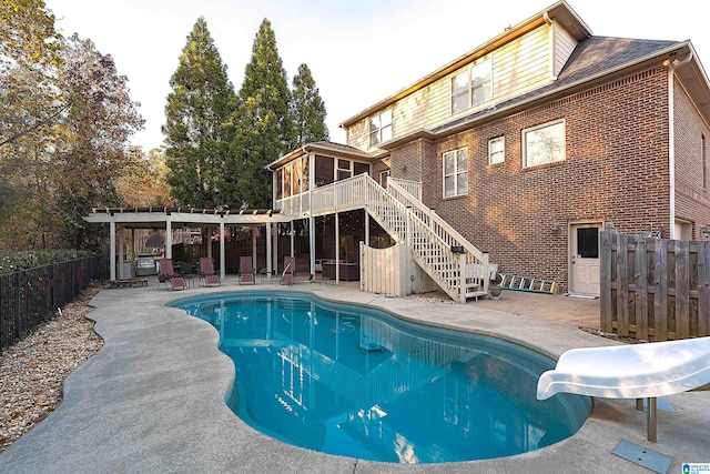 view of swimming pool with a sunroom, a patio, and a water slide