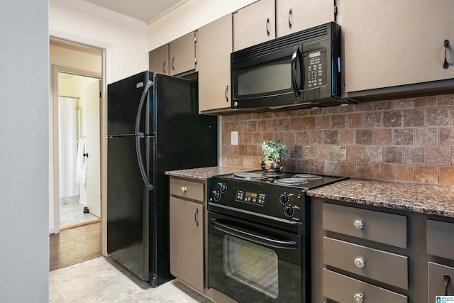 kitchen with light wood-type flooring, tasteful backsplash, dark stone countertops, and black appliances