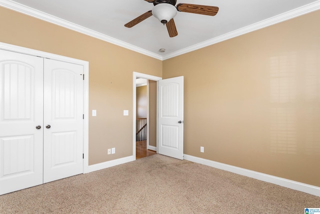 unfurnished bedroom featuring ceiling fan, ornamental molding, carpet floors, and a closet