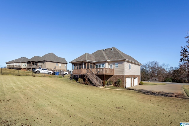 back of property featuring a lawn, a sunroom, a garage, and a wooden deck