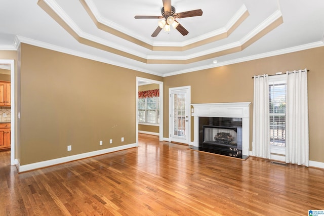 175 Smithfield Ln, Springville, AL 35146 - unfurnished living room featuring a tray ceiling, crown molding, light wood finished floors, ceiling fan, and baseboards