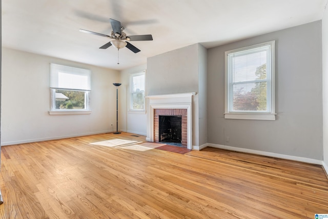 unfurnished living room featuring a fireplace, light hardwood / wood-style flooring, a wealth of natural light, and ceiling fan