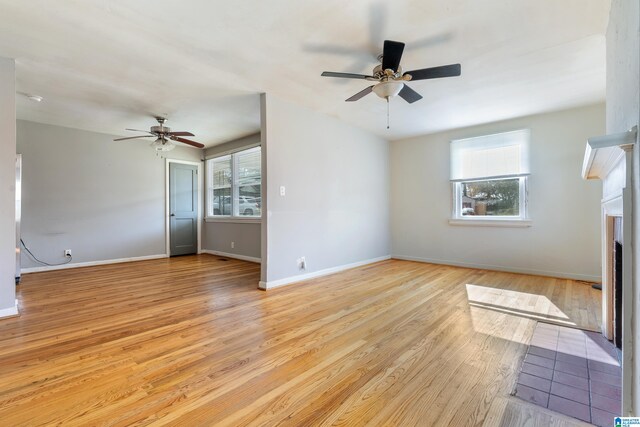 unfurnished living room featuring ceiling fan, a healthy amount of sunlight, and light wood-type flooring