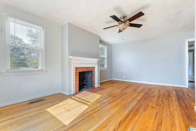 unfurnished living room with a fireplace, light wood-type flooring, and ceiling fan