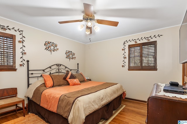 bedroom featuring multiple windows, light hardwood / wood-style floors, ceiling fan, and ornamental molding