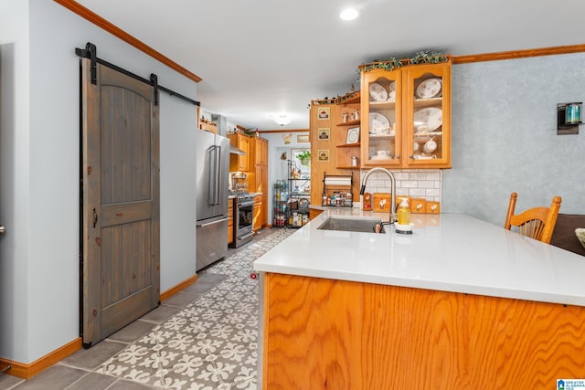 kitchen featuring kitchen peninsula, appliances with stainless steel finishes, ornamental molding, sink, and a barn door