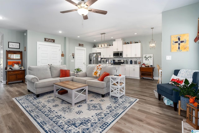 living room featuring hardwood / wood-style floors, ceiling fan with notable chandelier, and sink