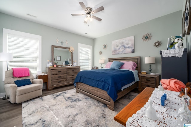 bedroom featuring dark hardwood / wood-style flooring, multiple windows, and ceiling fan