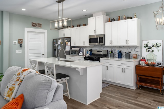 kitchen featuring appliances with stainless steel finishes, decorative light fixtures, a kitchen island with sink, and sink