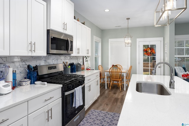 kitchen featuring sink, dark wood-type flooring, stainless steel appliances, decorative light fixtures, and white cabinets