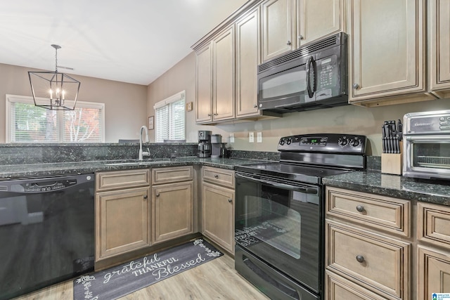 kitchen with sink, light hardwood / wood-style flooring, a notable chandelier, dark stone counters, and black appliances