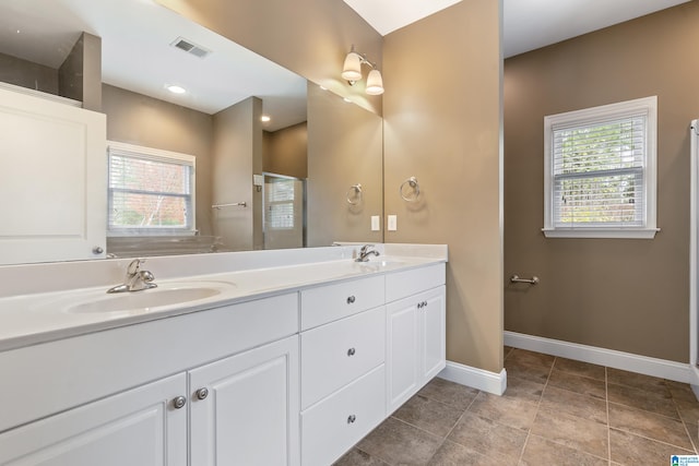 bathroom with tile patterned floors, plenty of natural light, vanity, and a shower with shower door