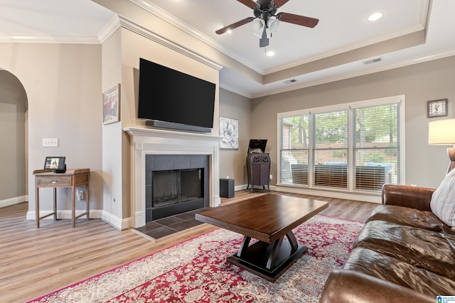 living room featuring hardwood / wood-style floors, ornamental molding, and a tile fireplace