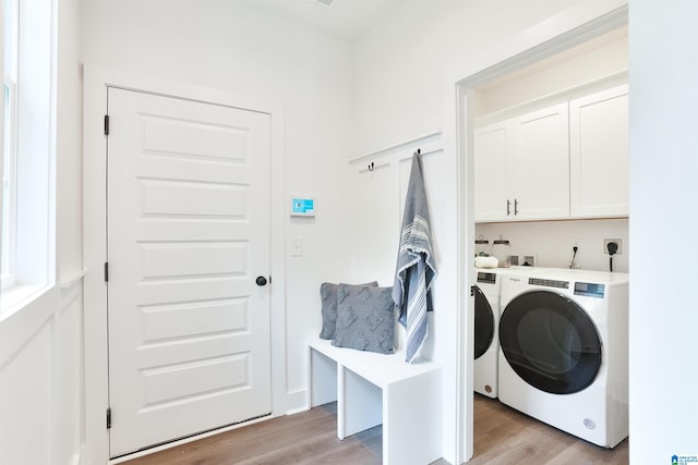 laundry area featuring cabinets, light hardwood / wood-style floors, and washing machine and clothes dryer