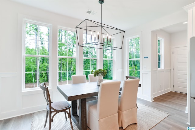 dining space featuring a healthy amount of sunlight, an inviting chandelier, and light hardwood / wood-style flooring