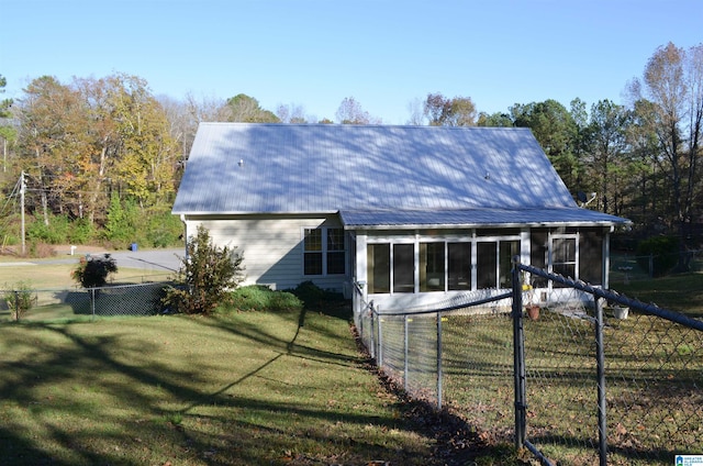 back of property with a sunroom and a lawn