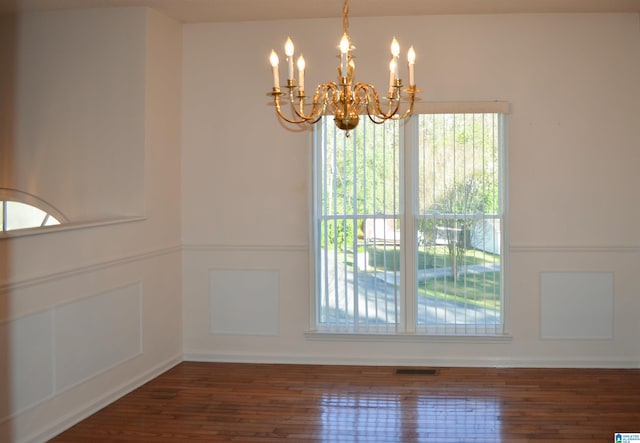 unfurnished dining area featuring dark hardwood / wood-style flooring and a notable chandelier