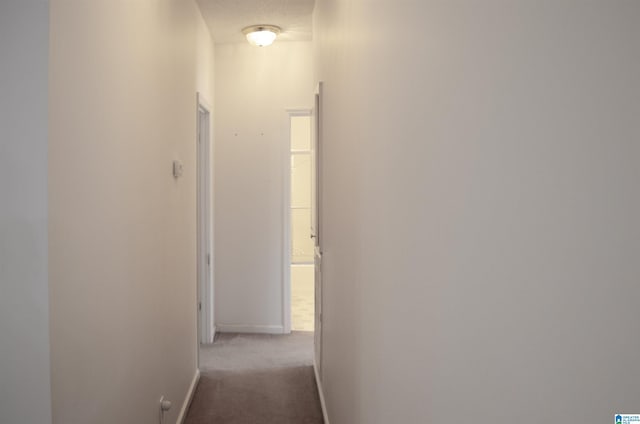 corridor with light carpet and a textured ceiling