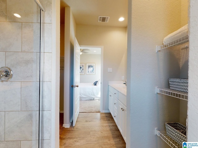 bathroom with vanity, wood-type flooring, and tiled shower