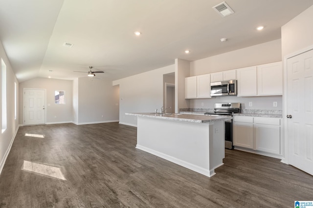 kitchen with ceiling fan, dark wood-type flooring, stainless steel appliances, a kitchen island with sink, and white cabinets