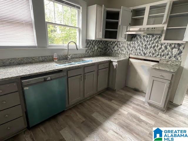 kitchen featuring sink, light stone counters, stainless steel dishwasher, backsplash, and light hardwood / wood-style floors