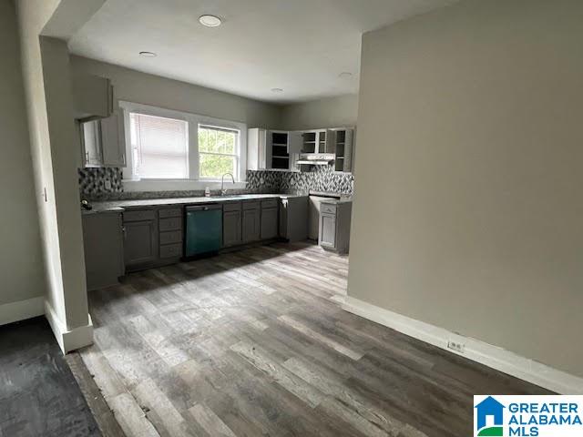 kitchen featuring hardwood / wood-style flooring, dishwasher, gray cabinets, and decorative backsplash