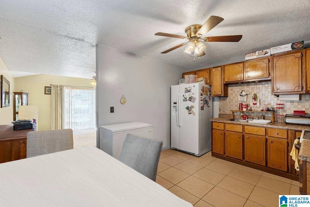 kitchen featuring sink, white refrigerator with ice dispenser, stove, a textured ceiling, and decorative backsplash