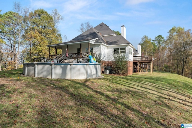 back of house with a swimming pool side deck and a yard