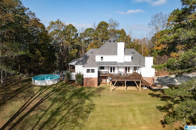 rear view of house featuring a lawn and a swimming pool side deck