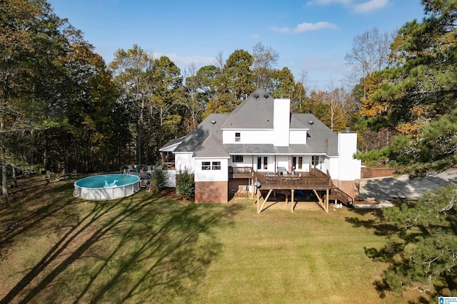 rear view of property with a swimming pool side deck and a yard