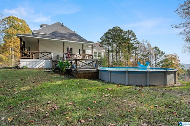 rear view of property with a yard and a pool side deck