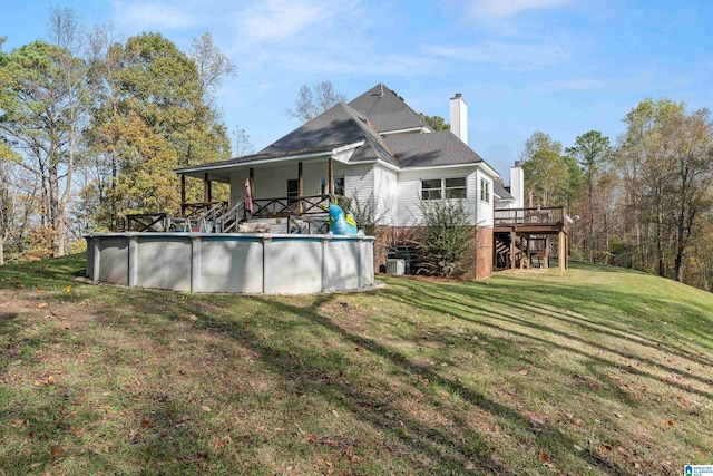 back of property with a lawn and a pool side deck