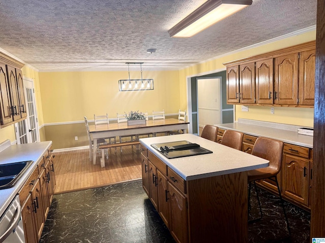 kitchen featuring a kitchen breakfast bar, ornamental molding, black cooktop, decorative light fixtures, and a kitchen island